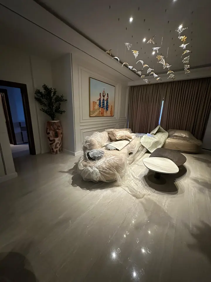 Living area with panelled walls, a sculptural ceiling feature and polished floor tiles