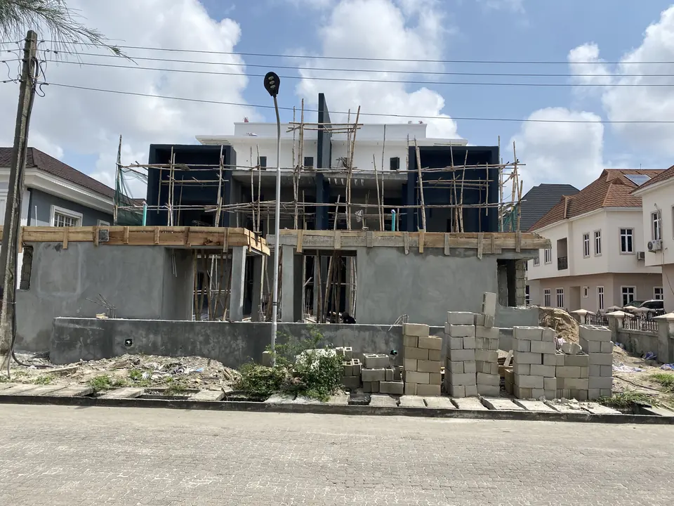 House frontage under construction with upper-floor cladding going on behind scaffolding